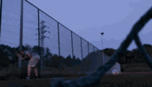 a blurry picture of a person standing next to a fence with a soccer ball in the background