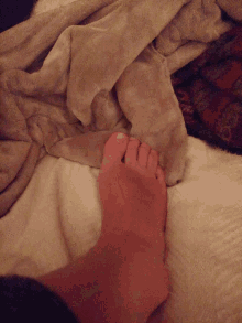 a person 's foot is resting on a blanket