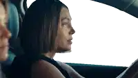 a woman is driving a car with another woman sitting in the back seat