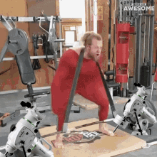 a man in a red suit is doing a squat in a gym