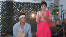 a man with a bandage on his head sits next to a woman in a pink saree