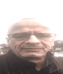 a bald man wearing glasses and a black jacket