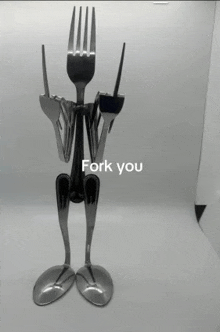 a statue of a man made out of forks and spoons with the words fork you written on it .