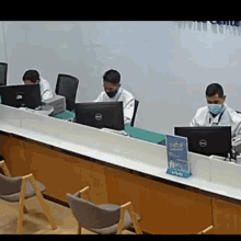 a man wearing a mask is sitting at a desk in front of a dell computer