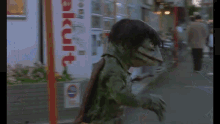 a man in a black suit is touching a green monster 's back