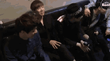 a group of boys are sitting on a couch and one of them is holding a cell phone .