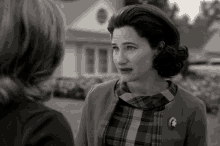 a woman in a plaid shirt has a button on her jacket that says ' a ' on it