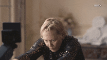 a woman is sitting in front of a screen with the word max on it
