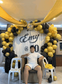 a man sitting in front of a wall that says emy @ 0