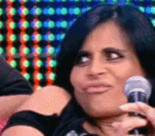 a woman is holding a microphone in her hand and making a face .