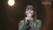 a girl in a green jacket singing into a microphone with the word crychic in the corner