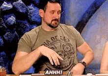 a man wearing a shirt that says dia de los muertos is sitting at a table
