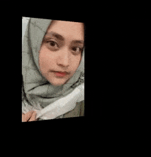 a close up of a woman wearing a hijab and a mask .