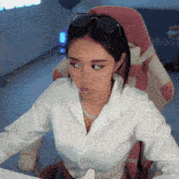 a woman wearing sunglasses and a white shirt is sitting in a pink chair