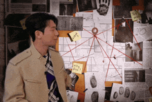 a man stands in front of a bulletin board with a sticky note on it that says " why five "