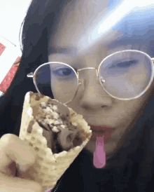 a woman wearing glasses is eating an ice cream cone
