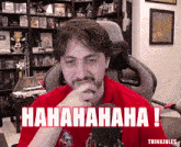 a man in a red shirt is sitting in front of a microphone with the words ' hahahaha ! ' on the screen