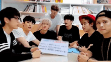 a group of young men are sitting around a table with a sign that says angels