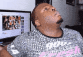 a man wearing a shirt that says ' god ' on it looks up at a computer screen