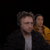 a man and a woman wearing headphones are looking at something