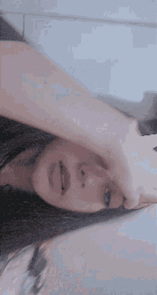 a close up of a woman 's face with her hand on her forehead .