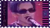 a man wearing sunglasses is singing into a microphone .