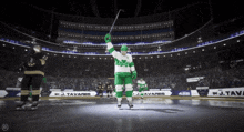 a hockey player in a green uniform holds up his stick