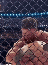 a man is behind a chain link fence in a boxing match