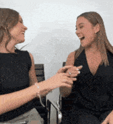 two women sitting next to each other laughing and one has a ring on her finger