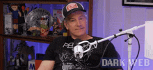 a man sitting in front of a microphone with dark web written in the corner