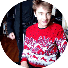 a boy wearing a red sweater with reindeer on it is smiling