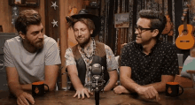 three men are sitting at a table with a microphone .