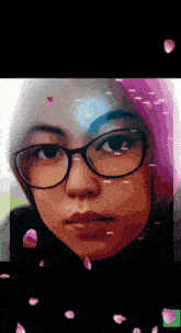 a woman wearing glasses and a pink hijab is surrounded by petals