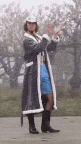 a man wearing a robe and cowboy boots stands on a sidewalk