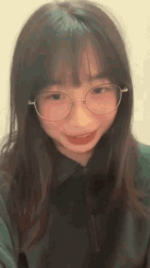 a young girl wearing glasses and a green jacket is smiling