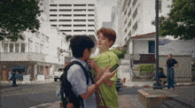 a man in a green shirt holds another man 's neck