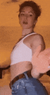a woman in a white tank top and blue jeans is dancing in a room .