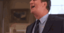 a man in a suit and tie is screaming in a living room .