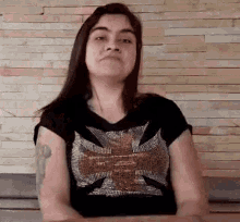 the woman is wearing a black shirt with a cross on it .