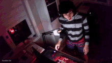 a person wearing headphones is standing in front of a computer with the name aurelion sol on the bottom right