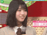 a girl is smiling while holding a microphone with chinese writing on the bottom