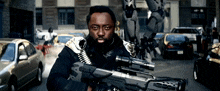 a man holding a gun with a sniper scope on it in a city street
