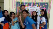 a group of young people posing in front of a happy teach day sign