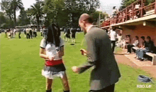 a man in a suit is standing next to a woman in a skirt on a grassy field .