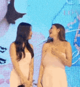 two women in white dresses are standing next to each other on a stage .