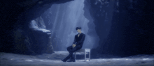 a man in a suit sits in a chair in a cave