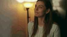 a woman is sitting in front of a lamp looking up