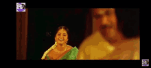 a woman in a green sari is smiling while standing next to a man .