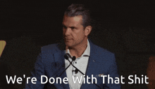 a man in a suit is giving a speech with the words we 're done with that shit behind him