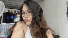 a young woman wearing glasses and a white tank top